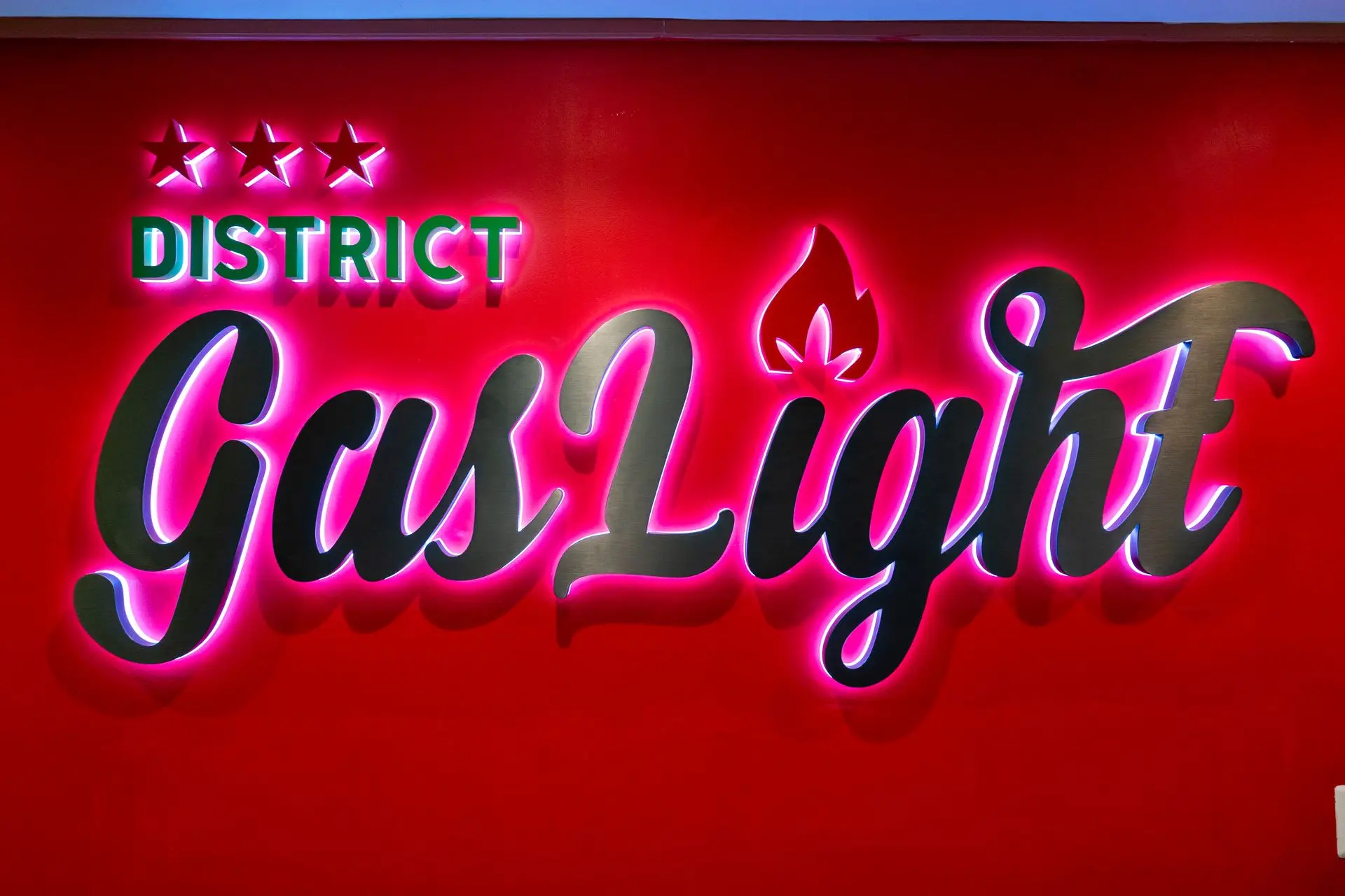 Illuminated District Gaslight sign on a red wall